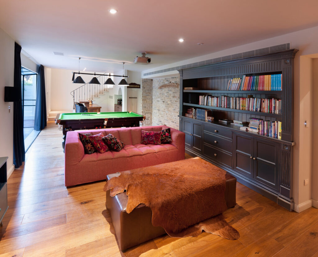 Recreation room with bookshelf and couch and hardwood floors