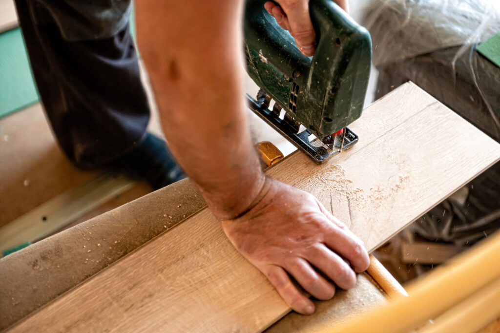 Worker installing laminate flooring by cutting plank