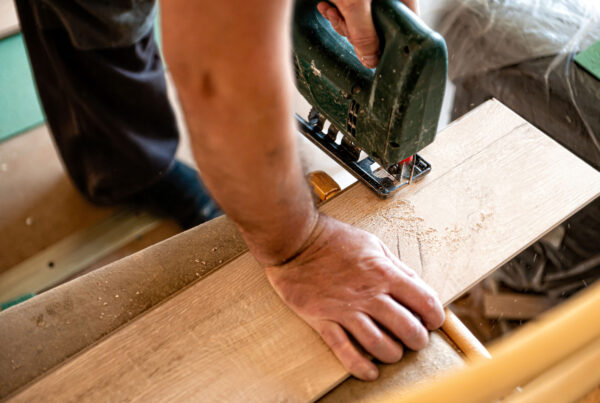 Worker installing laminate flooring by cutting plank