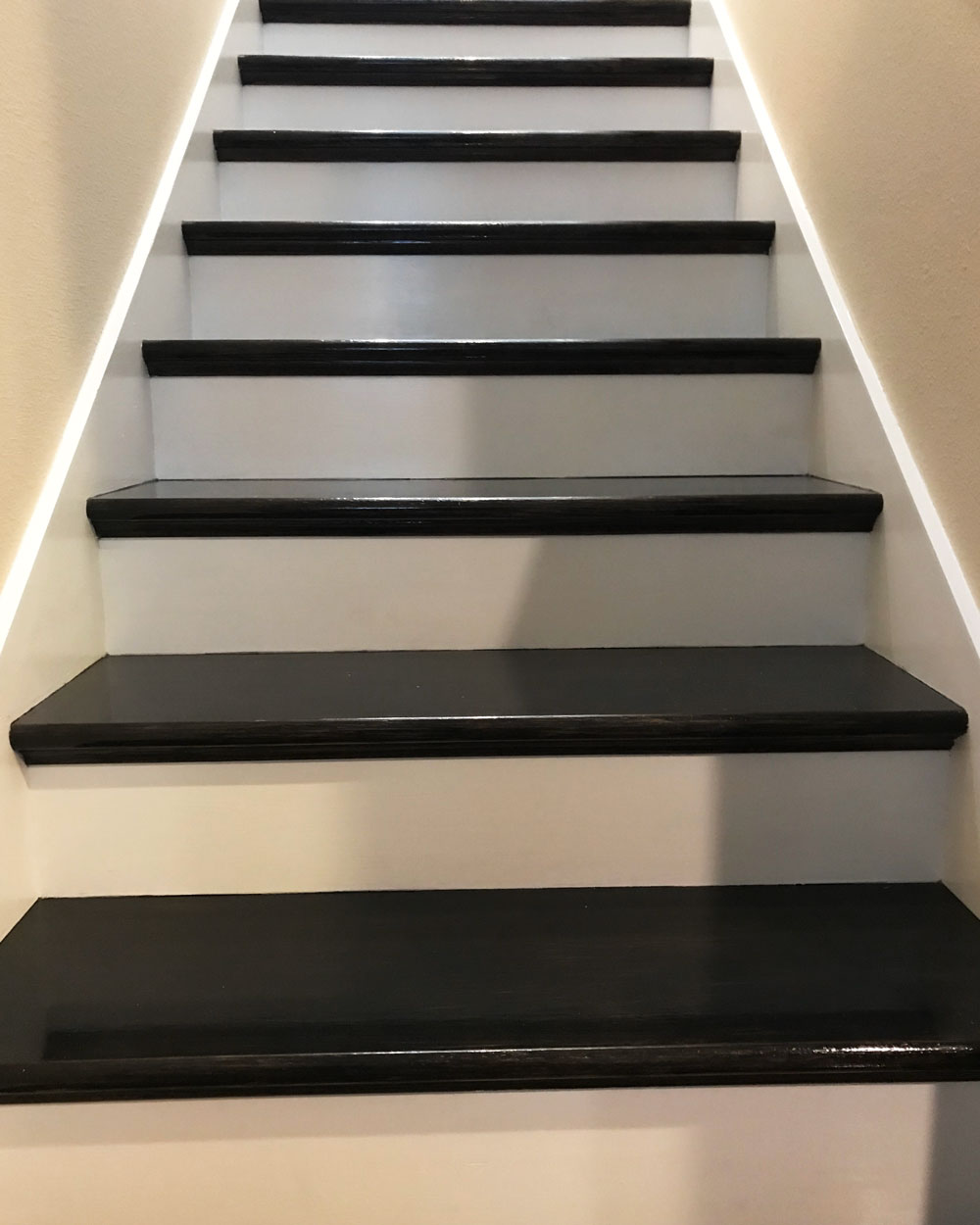 Staircase with black hardwood planks and white risers
