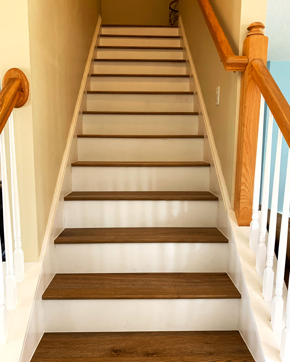 Staircase with brown hardwood planks and white risers